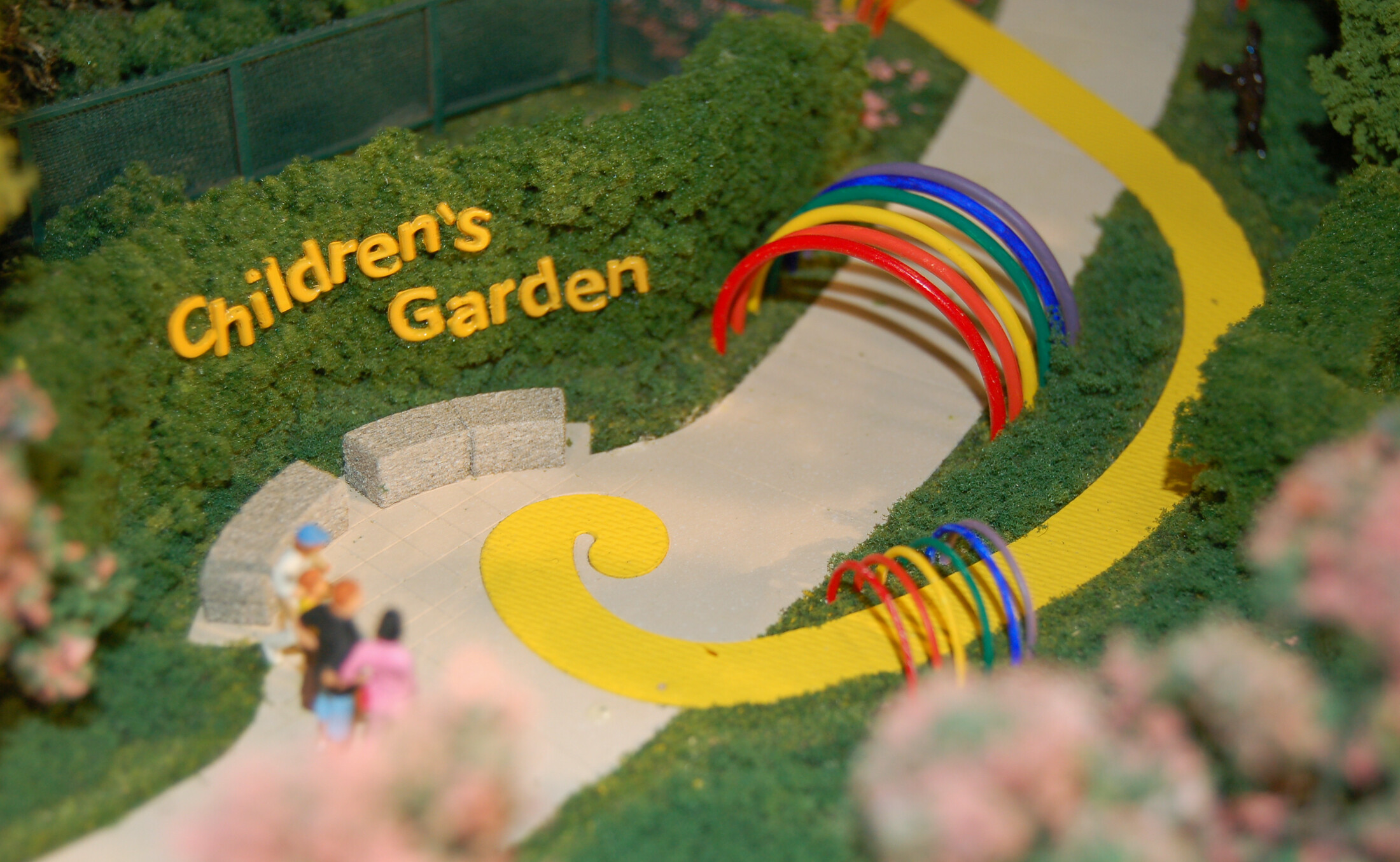 Children’s Botanical Garden model with rainbow entry arches, miniature visitors and planted paths.