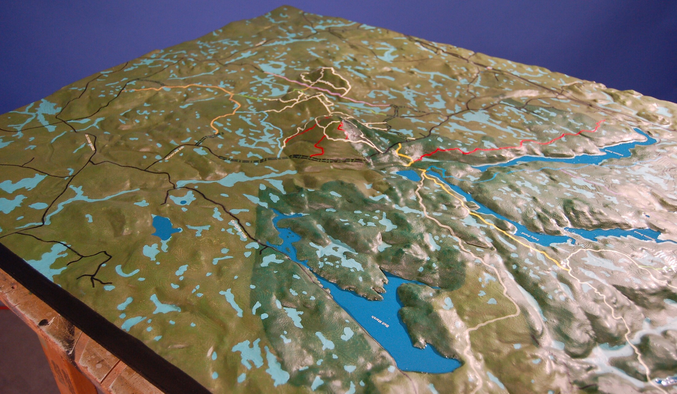 Mount Agamenticus relief model with raised hills, blue waterways, roads and colored trails.